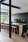 Modern kitchen with black front, wooden counter and wooden bar stools