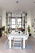 Bright dining area with white table, white chairs and designer chandelier