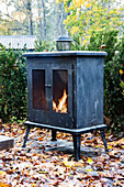 Black patio stove surrounded by autumn leaves in the garden