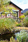 Herbstliche Stimmung im Garten mit Gewächshaus und Teich