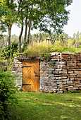 Natural stone structure with wooden door and grass roof in the garden