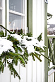 Fensterbank mit schneebedeckten Tannenzweigen