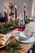 Festive wooden table with red candles and fir branches