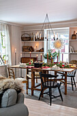 Wooden table with Christmas decorations, candles and fir branches in the dining room