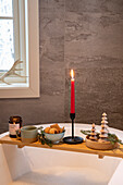 Bathtub shelf with candle, snacks and Christmas decorations in the bathroom