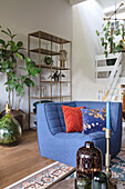 Blue armchair with decorative throw pillows, indoor plants and metal shelf