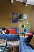 Living room with blue sofas, mustard yellow walls and green floor lamp