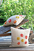 Wooden lounger in the garden with decorative cushions with floral embroidery