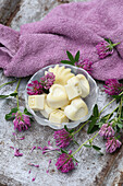 Homemade soaps in heart and shell shapes with fresh clover on a rustic wooden board