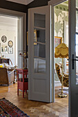 Open door to living room with parquet floor and patterned armchair