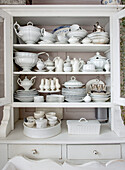 Filled white vintage crockery cupboard with ceramics and porcelain