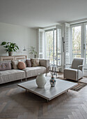 Monochrome living room with corner sofa, coffee table and herringbone parquet flooring