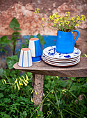 Ceramic crockery and vase in white and blue with yellow wildflowers on a rustic wooden table