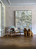 Armchair with striped upholstery in front of large abstract artwork and two dogs on wooden floor