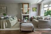 Classic living room with fireplace, beige sofas, wooden table and green plants