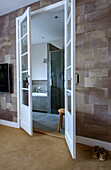 View through French doors into bathroom with glass shower and bathtub