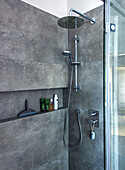 Modern shower with dark grey wall tiles, built-in shelf and rain shower head