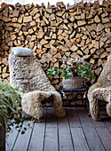 Cozy seating area with sheepskin armchairs in front of a stack of firewood