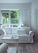 White living room with wooden floorboards and view of the garden