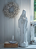 Madonna statue with rosary and candle on windowsill