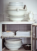 Vintage porcelain crockery and cloths in white kitchen cupboard