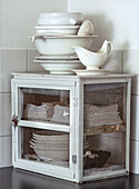 Vintage cupboard with stacked white cloths and porcelain crockery