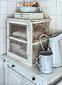 Cupboard in vintage kitchen with ceramic jug, enamel mug and soap bars