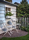 White bistro seating area in front of garden shed with window flower box