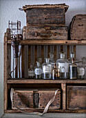 Old wooden shelf with vintage glass bottles and antique wooden boxes