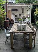 Garden dining area with wooden table, metal chairs and outdoor kitchen in the background