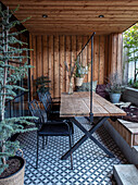 Moderne, überdachte Terrasse mit Holzwand und gemustertem Fliesenboden