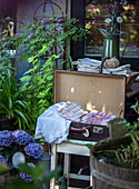 Open suitcase with lace and linen cloths in a rustic garden