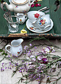 Vintage tea service with floral pattern on rustic tray and wildflower bouquet