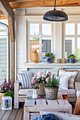 Covered terrace with wooden furniture, lanterns and flower pots