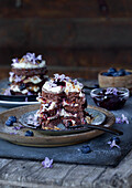 Chocolate tartlets with berries and flowers on a rustic wooden table