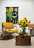 Reading corner with yellow armchair and sunflowers (Helianthus)