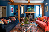 Living room with wooden beams, blue walls and two velvet sofas