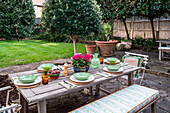 Set wooden table in the garden with flower pot and bowls in shades of green