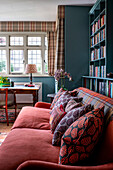 Living room with red sofa, patterned cushions and bookshelf in front of window front