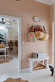 Entrance area with pastel pink walls, white furniture and jute rugs