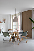 Dining area with wooden table, various chairs and wood panelling on the wall