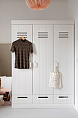 White wardrobe with hanging T-shirt and jute bag in the bedroom