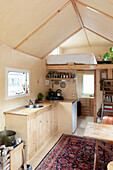 Small kitchen with wooden panelling and sleeping area in a tiny house