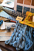 Fabrics and yarn in different shades of blue with colour samples on table