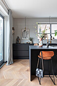 Modern kitchen with black cabinets, hanging lamps and white tiled wall