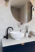 Modern bathroom with round mirror and black tap