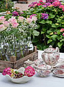 Vintage tea service with bouquets of roses and hydrangeas on a garden table