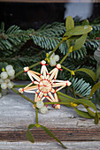 Straw star and mistletoe branches on a rustic wooden table