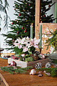 Christmas decorated table with green candles and poinsettia in wooden box