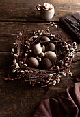 Osternest mit Weidenkätzchen und Eiern auf rustikalem Holztisch